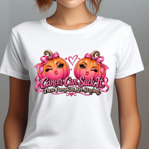 A model wearing a white short-sleeve crewneck t-shirt  for Breast Cancer Awareness, combines spooky season with Pink October in one fabulously sassy design. Two glamorous pink-and-orange pumpkins are decked out with sparkling rhinestones, oversized pink bows and plenty of personality, pursing their lips, finished with the unapologetic message “Cancer Can Suck It. These Pumpkins Are Staying.”