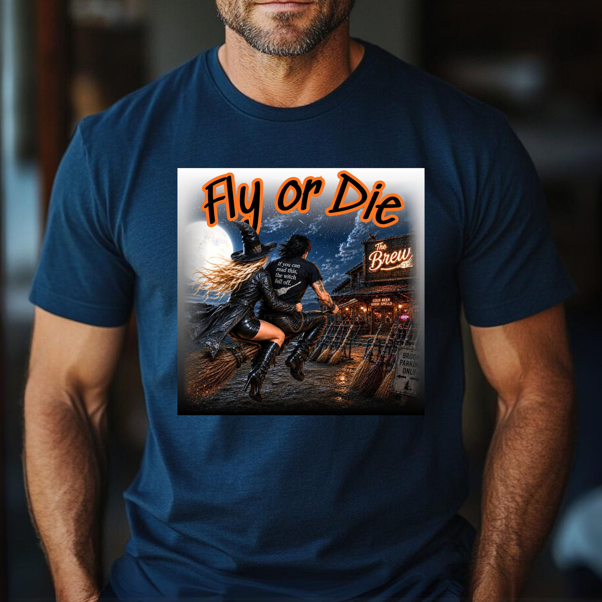 A man wearing a navy blue t-shirt with a large graphic print on the chest. Made for witches with a wild side, this bold Halloween design features a badass witchy couple tearing through the moonlit night on their broom, headed straight for The Brew—where the beer is cold, the spells are good, and broom parking is always available. With her hair and leather coat flying in the wind and his shirt delivering the warning, “If you can read this, the witch fell off,” this design brings the Halloween.