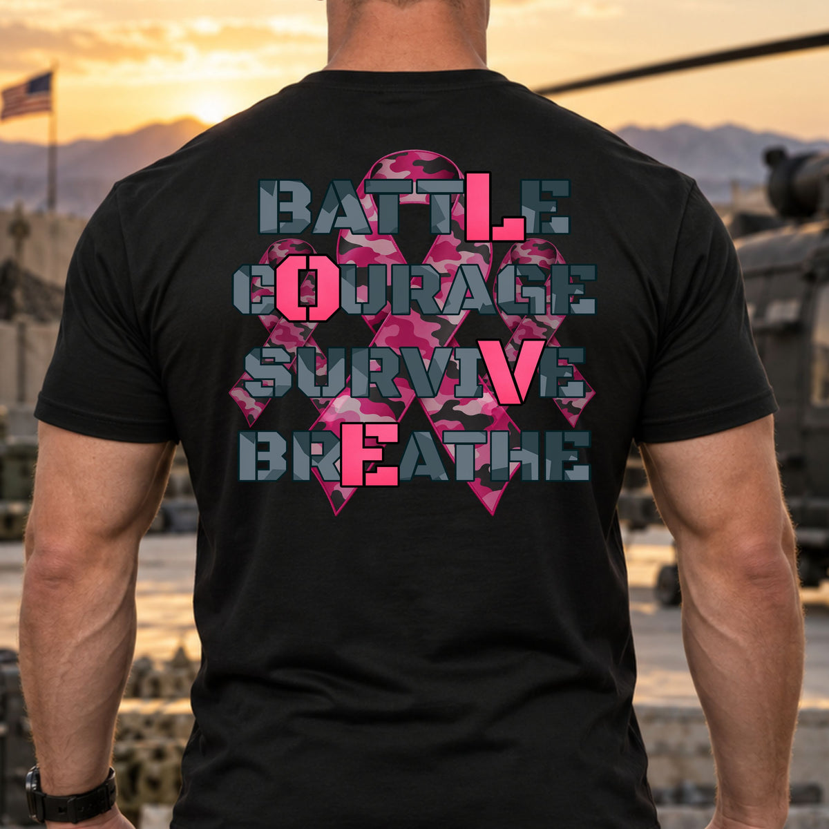 A man viewed from behind wearing a black t-shirt with a large graphic on the back. The graphic features a pink camouflage ribbon overlaid with the words 'BATTLE COURAGE SURVIVE BREATHE' in a distressed gray font. The "L" from BATTLE is in bright pink, along with the "O" from COURAGE, "V" from SURVIVE, and "E" from BREATHE, showing the word LOVE, set against a military base background at sunset.                                                                      

