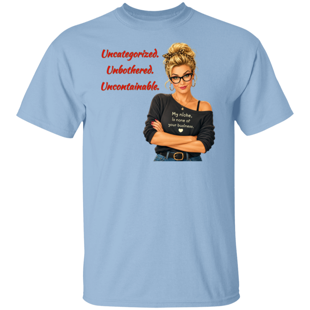 A light blue short-sleeve t-shirt with a graphic print on the front. The graphic features a retro-style illustration of a blonde woman in glasses wearing a black off-the-shoulder shirt with the text  'My niche, is none of your business.", along with "Uncategorized", "Unbothered", "Uncontainable" written in red letters.