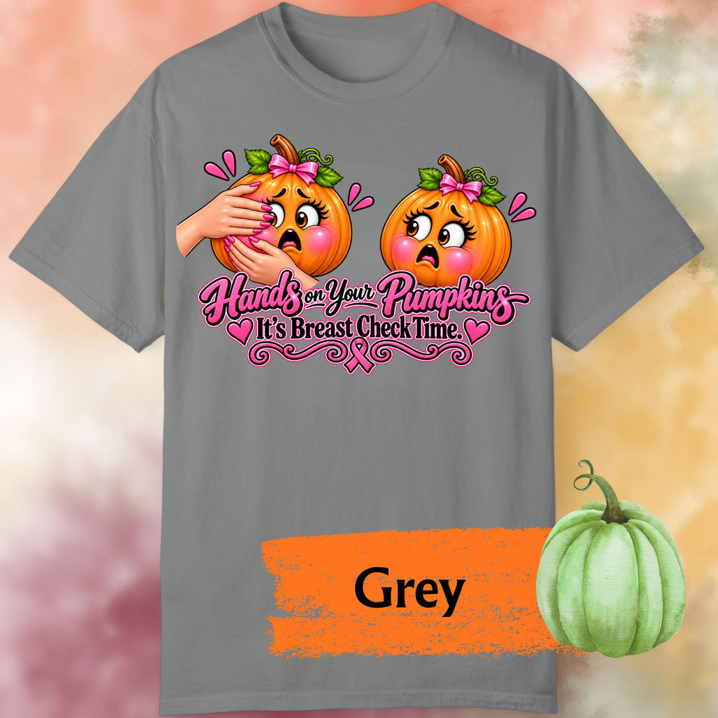 A grey short-sleeve graphic t-shirt, featuring a humorous  important reminder with this funny Breast Cancer Awareness Shirt, created for women who like their Pink October message with a little sass. This playful Breast Cancer Awareness Halloween design features two adorably horrified pumpkins, pink bows, pink accents, a breast cancer awareness ribbon and the cheeky reminder: “Hands on Your Pumpkins — It's Breast Check Time!” while what hands are squeezing the one pumpkin for lumpkins.