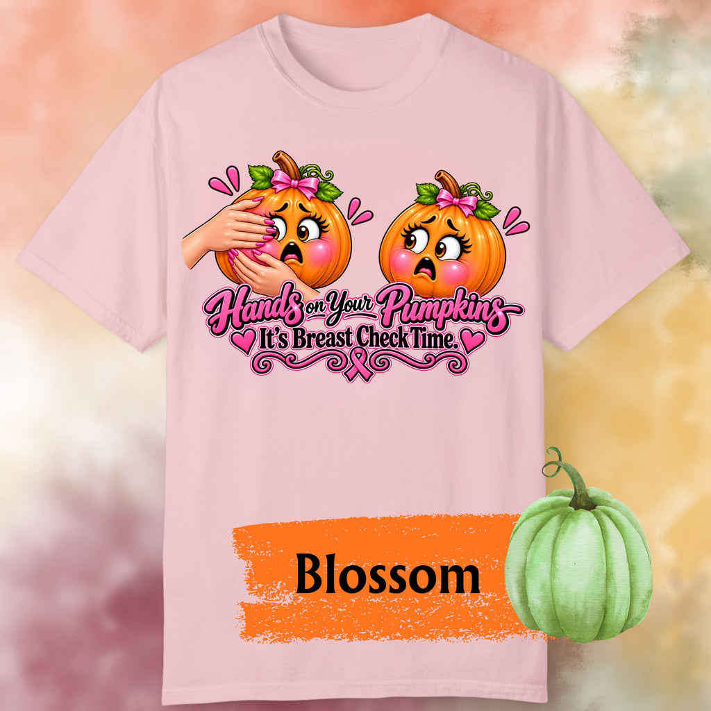 A light pink short-sleeve graphic t-shirt, featuring a humorous  important reminder with this funny Breast Cancer Awareness Shirt, created for women who like their Pink October message with a little sass. This playful Breast Cancer Awareness Halloween design features two adorably horrified pumpkins, pink bows, pink accents, a breast cancer awareness ribbon and the cheeky reminder: “Hands on Your Pumpkins — It's Breast Check Time!” while what hands are squeezing the one pumpkin for lumpkins.